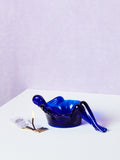 Blue plastic bathing lady dish on a white surface with a light purple background