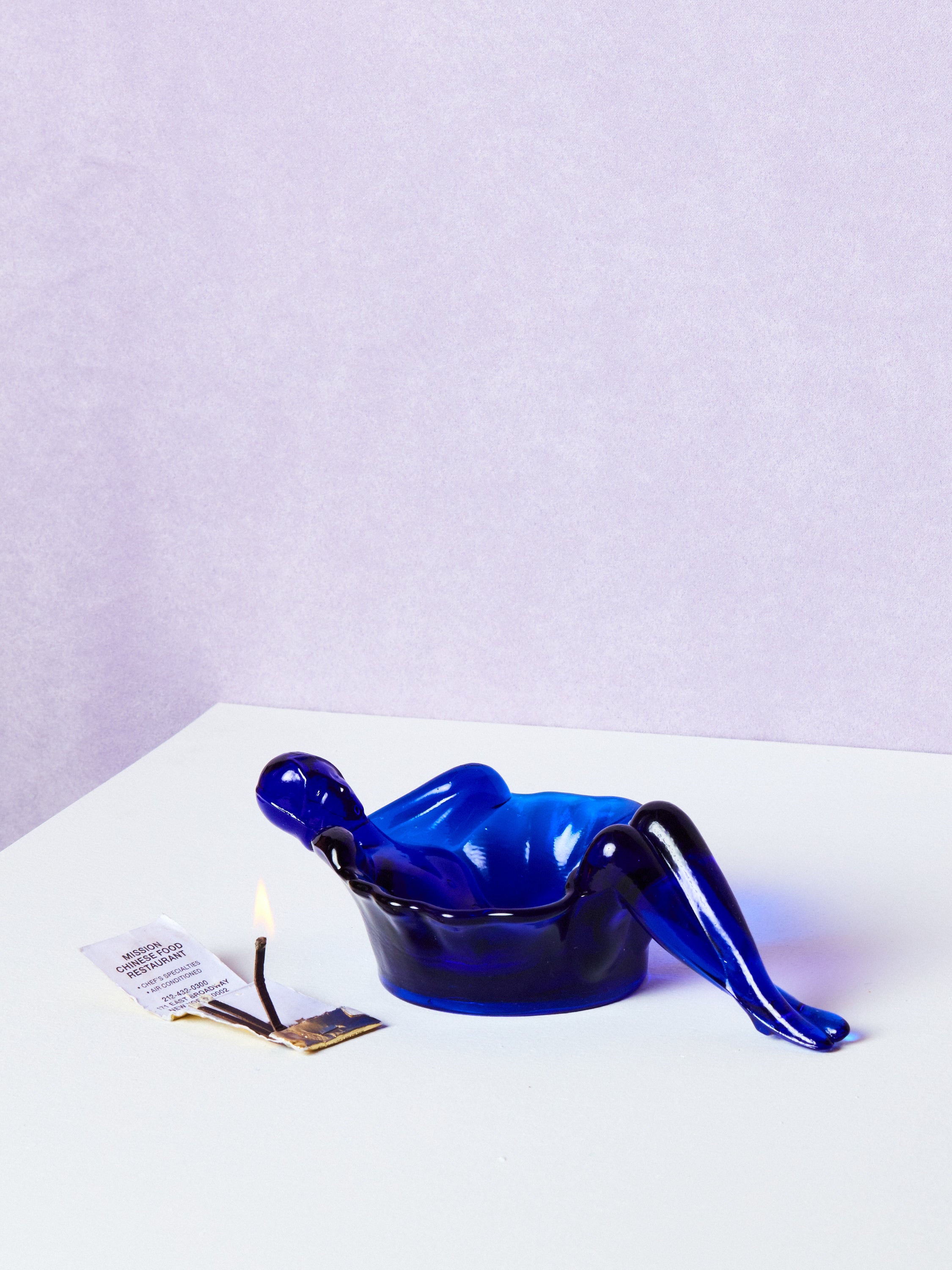 Blue plastic bathing lady dish on a white surface with a light purple background