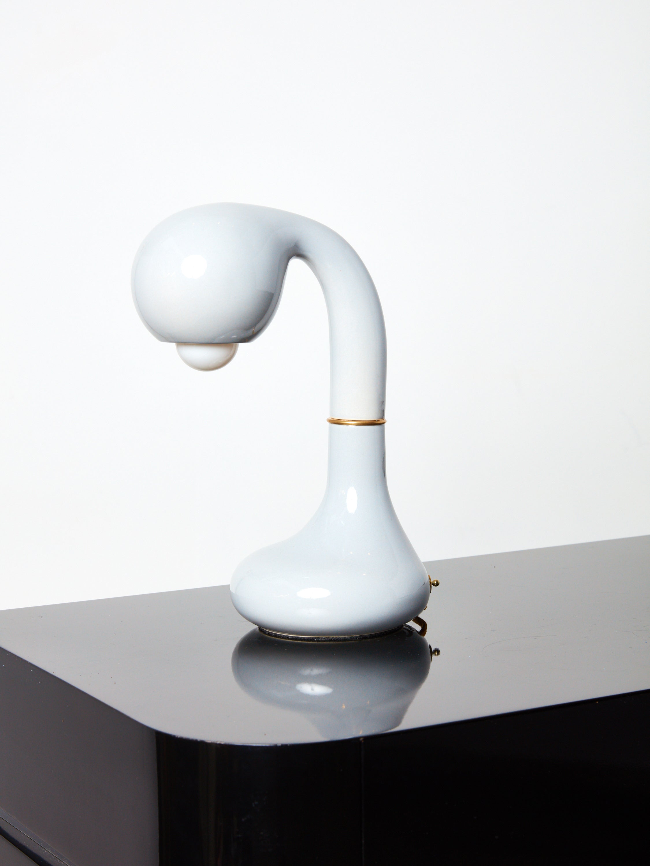 White  Short Ceramic Table Lamp by Entler Studio on a glossy black surface.