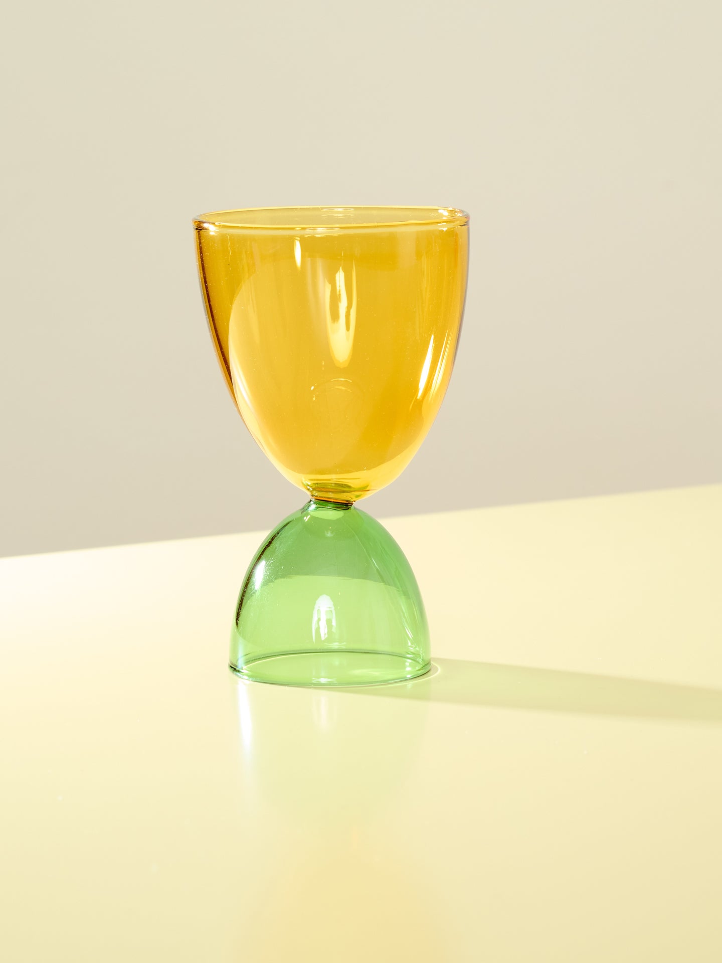 A yellow top and green bottom cocktail glass.