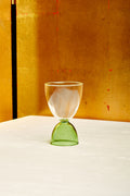 A clear top green bottom cocktail glass.