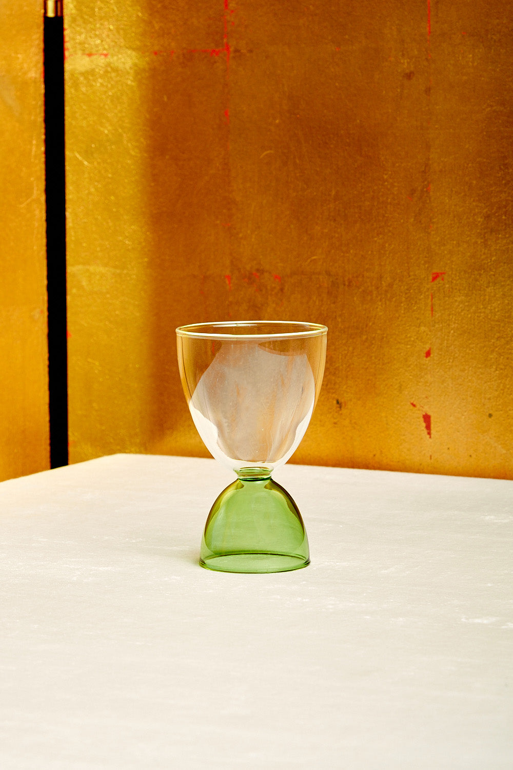 A clear top green bottom cocktail glass.