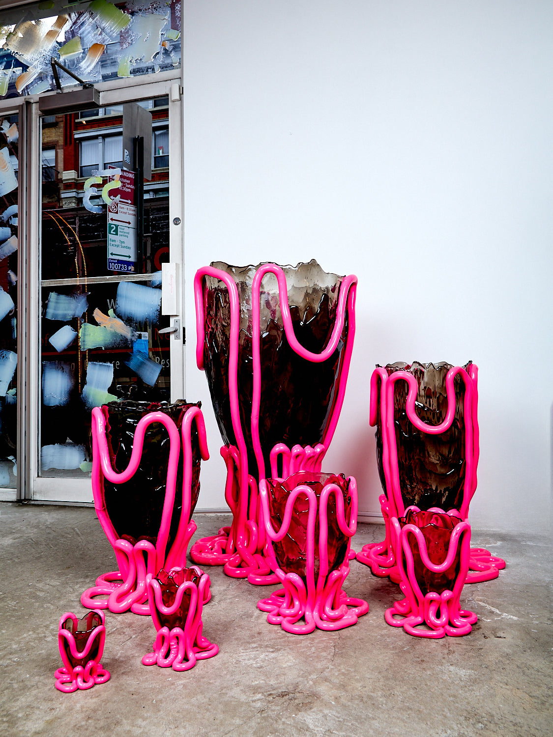 Set of smoke grey and hot pink Indian Summer vessels on a concrete floor against a white wall.