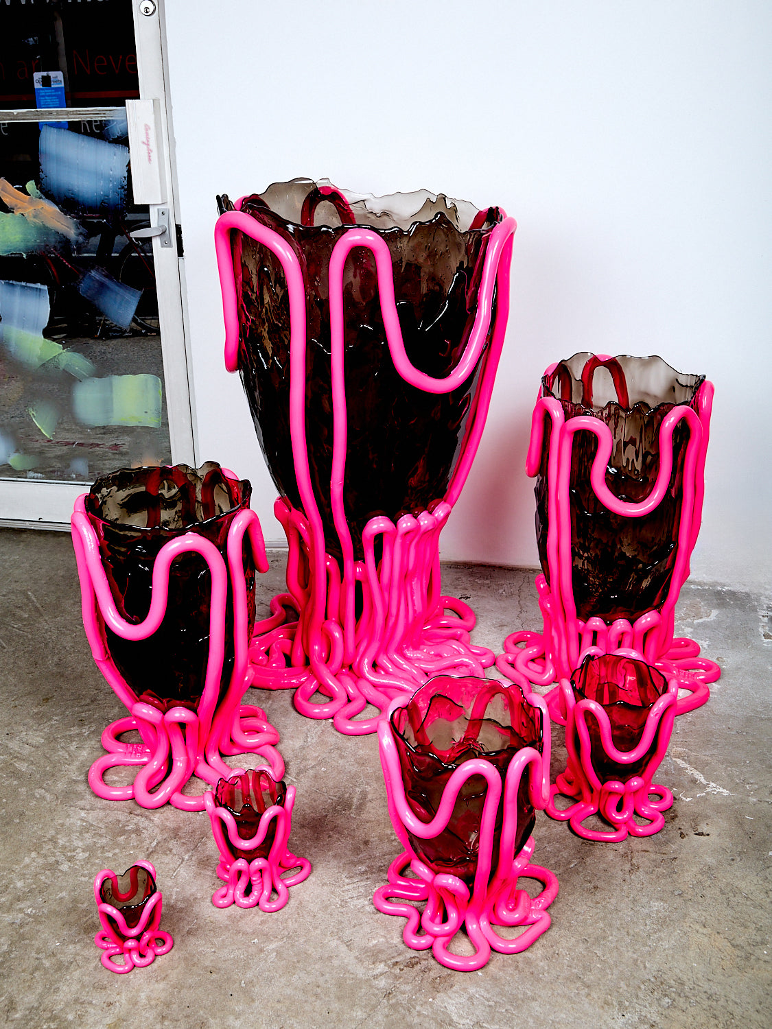 Seven hot pink and smoke indian summer vessels in varying sizes.