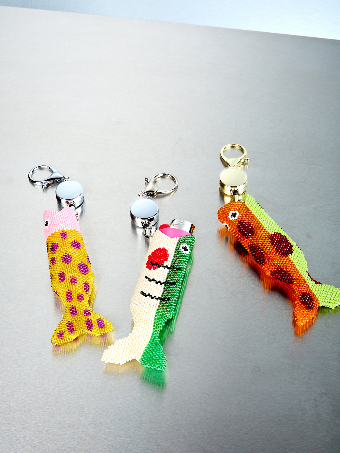 Three colorful keychains shaped like fish on a metallic surface