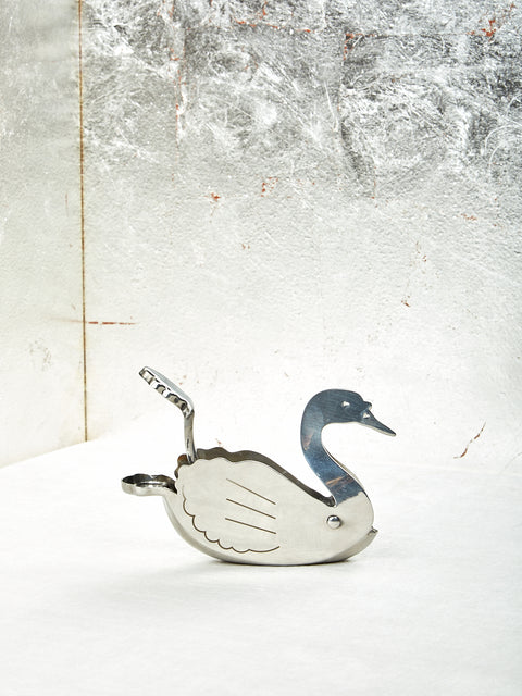 A silver Swan lemon squeezer with a decorative bird design on a textured background.