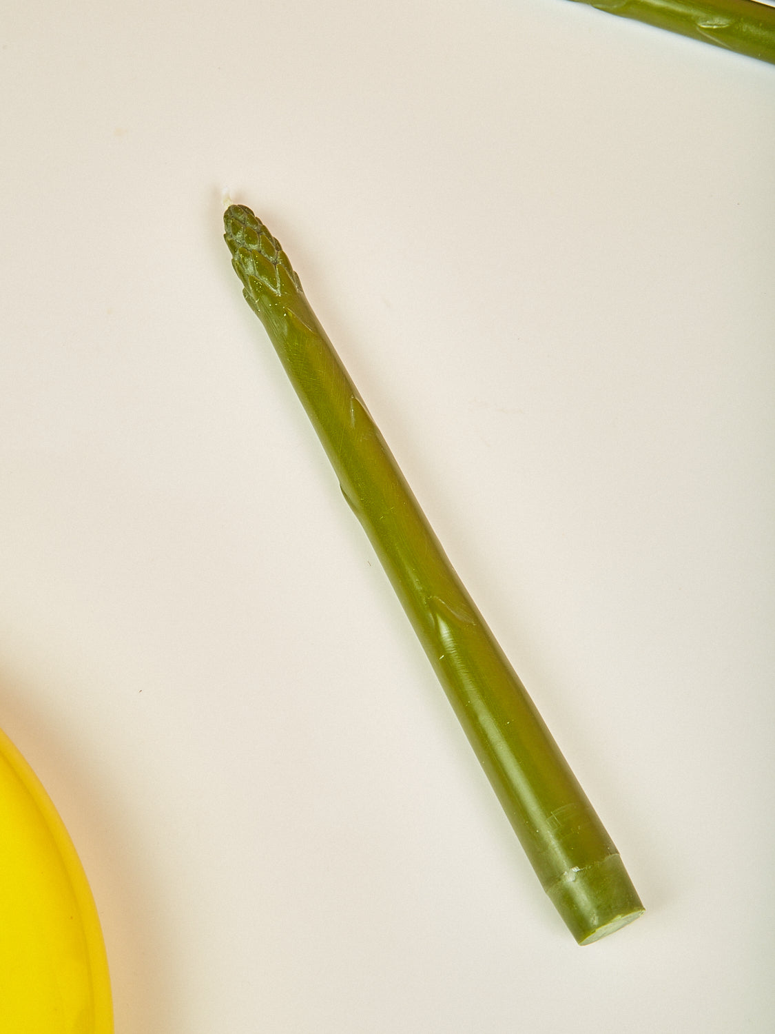 Single asparagus candle on a white background