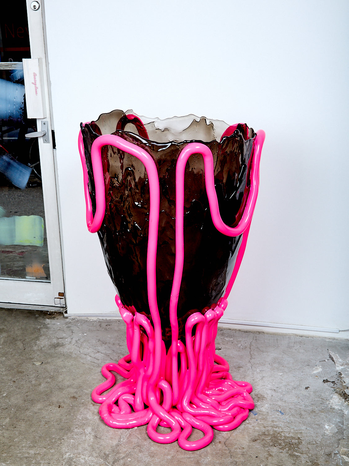 Vase with pink base and black body on a concrete floor
