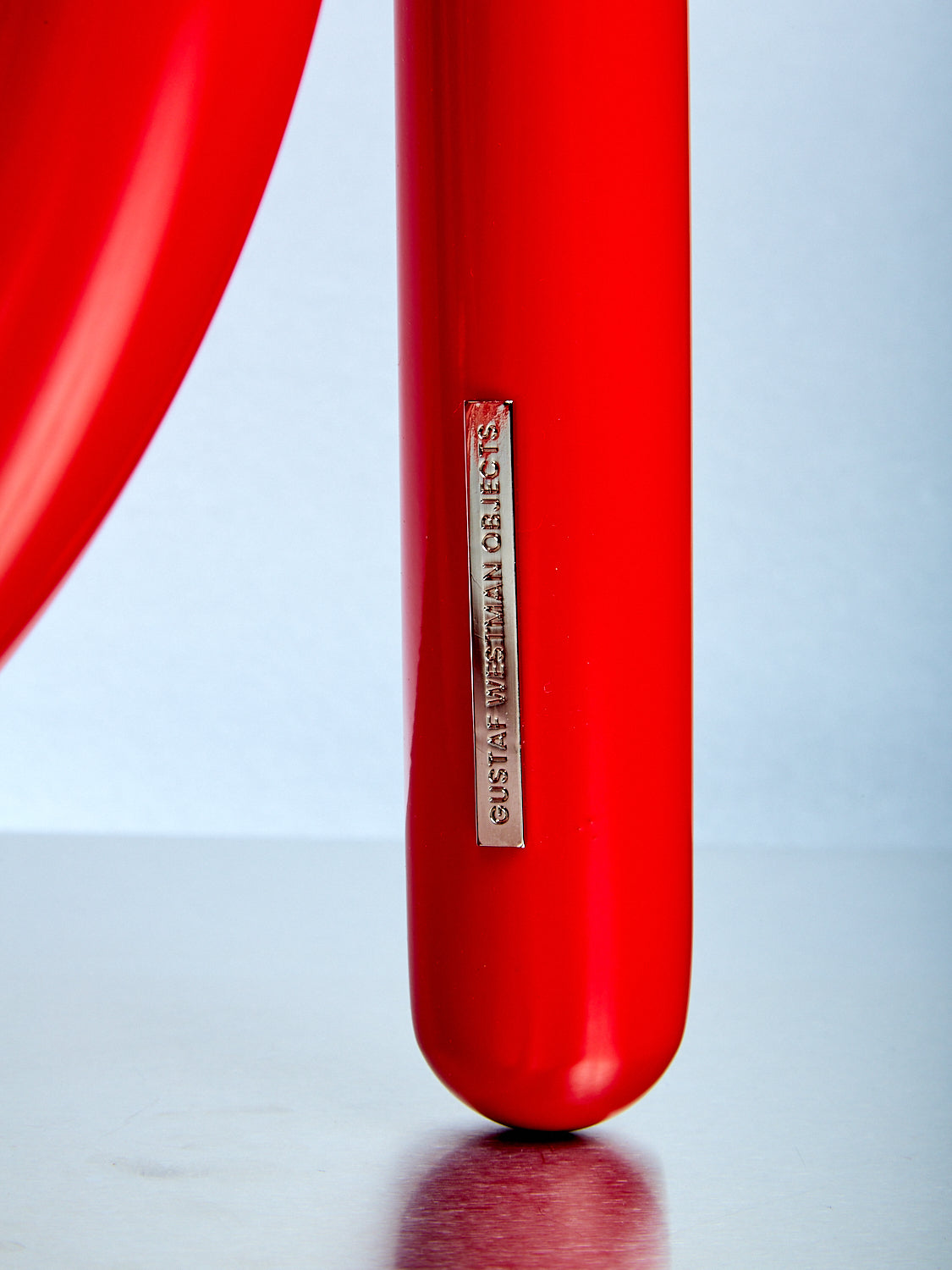 Close-up of a red object with a visible brand logo on a light blue background