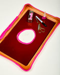Red tray with pink border containing stationery items on a white background