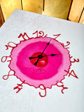 Pink clock with red numbers on a white background