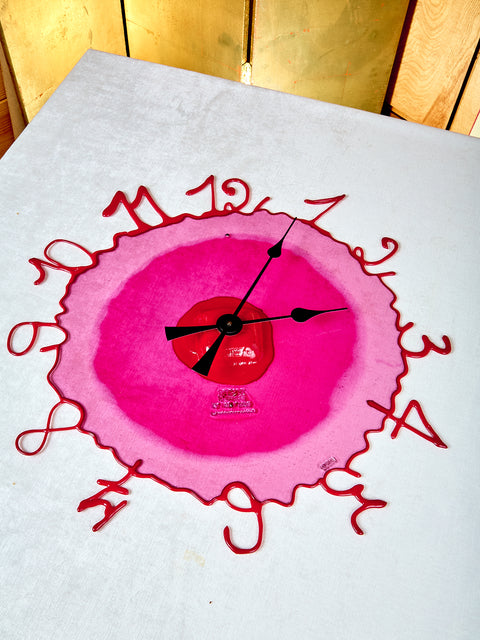 Pink clock with red numbers on a white background