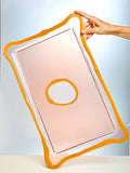 Rectangular pink pad with a circular cutout, held by a hand against a light blue background