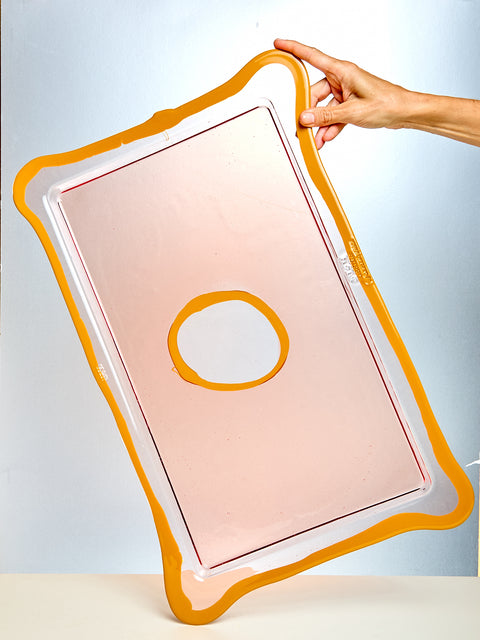 Rectangular pink pad with a circular cutout, held by a hand against a light blue background