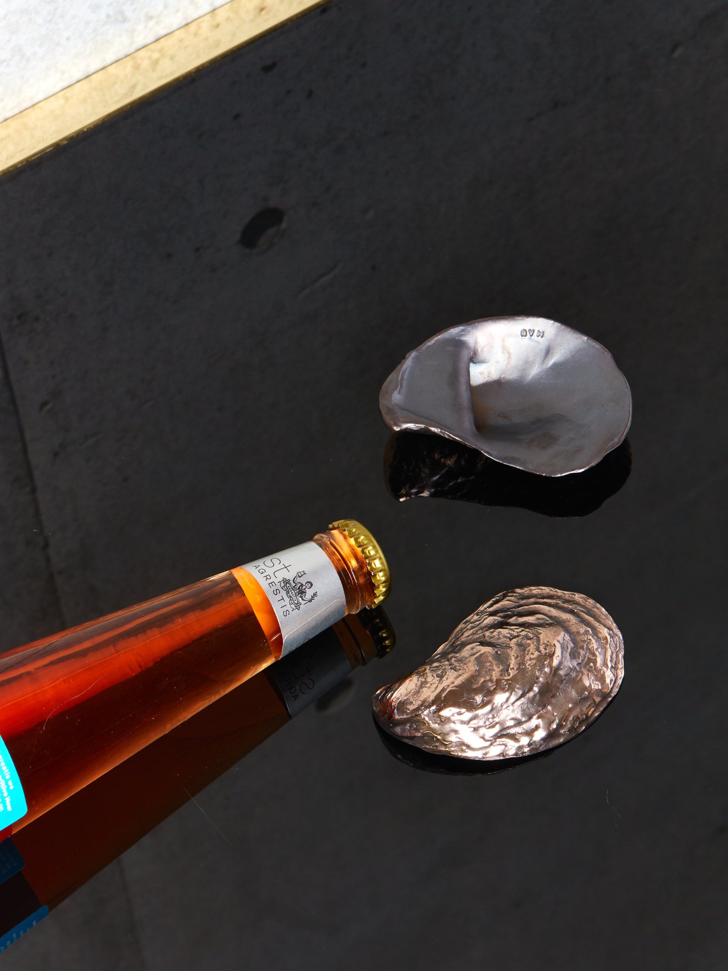 A bottle lays beside two oyster bottle openers.